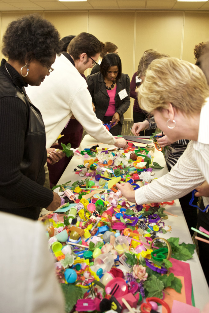 Creative Community Conversations participants with the table of found objects used by James Rojas. Photo by Chris Nowak, Michigan Fitness Foundation